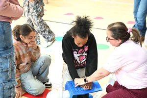 Students performed CPR on training dummies, learning to lock their arms straight and use their body weight to deliver effective chest compressions