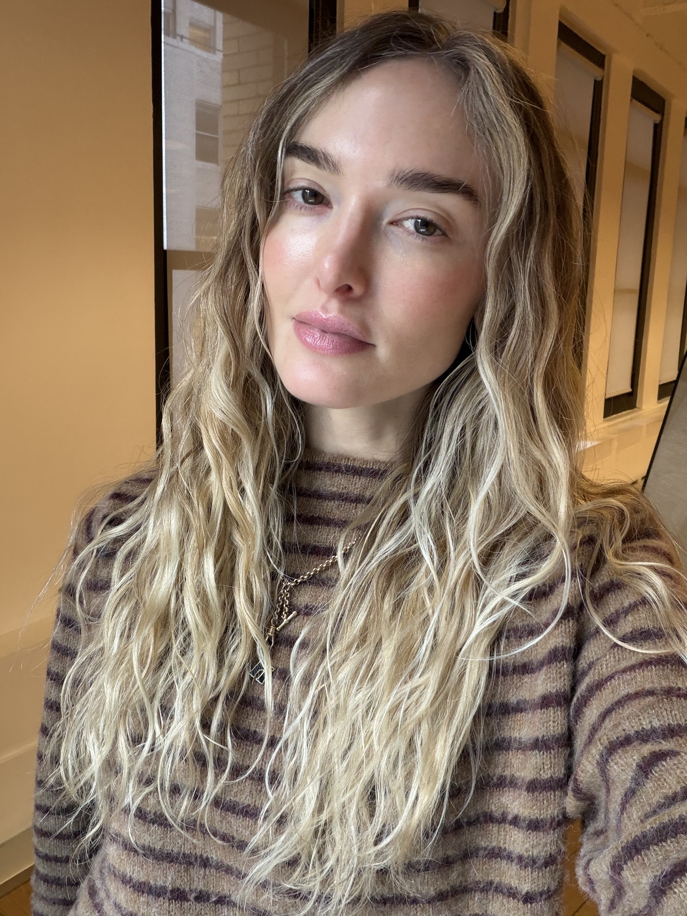 a blonde woman with long wavy hair in a striped sweater