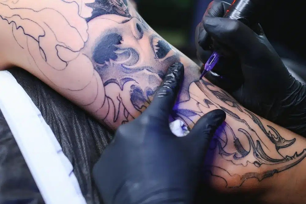 Male,tattoo,artist,holding,a,tattoo,gun,,showing,a,process