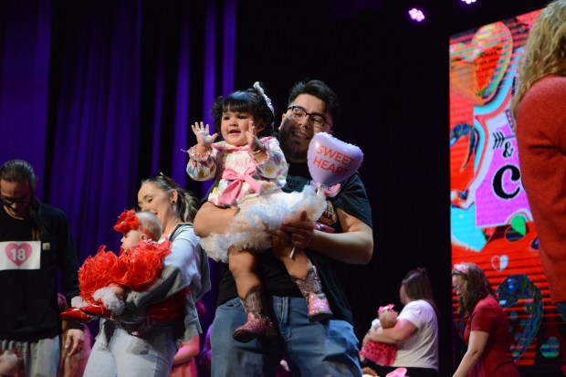 One-year-old Lumina Esquibel blows kisses to the audience alongside her dad, Manuel Esquibel. (Sharla Steinman/ Loveland Reporter-Herald)