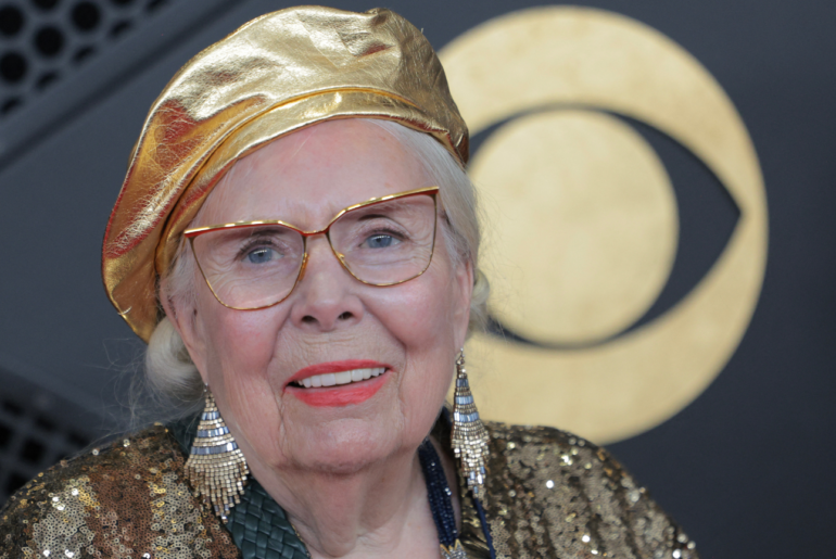 an older white woman with a red lipstick and gold outfit