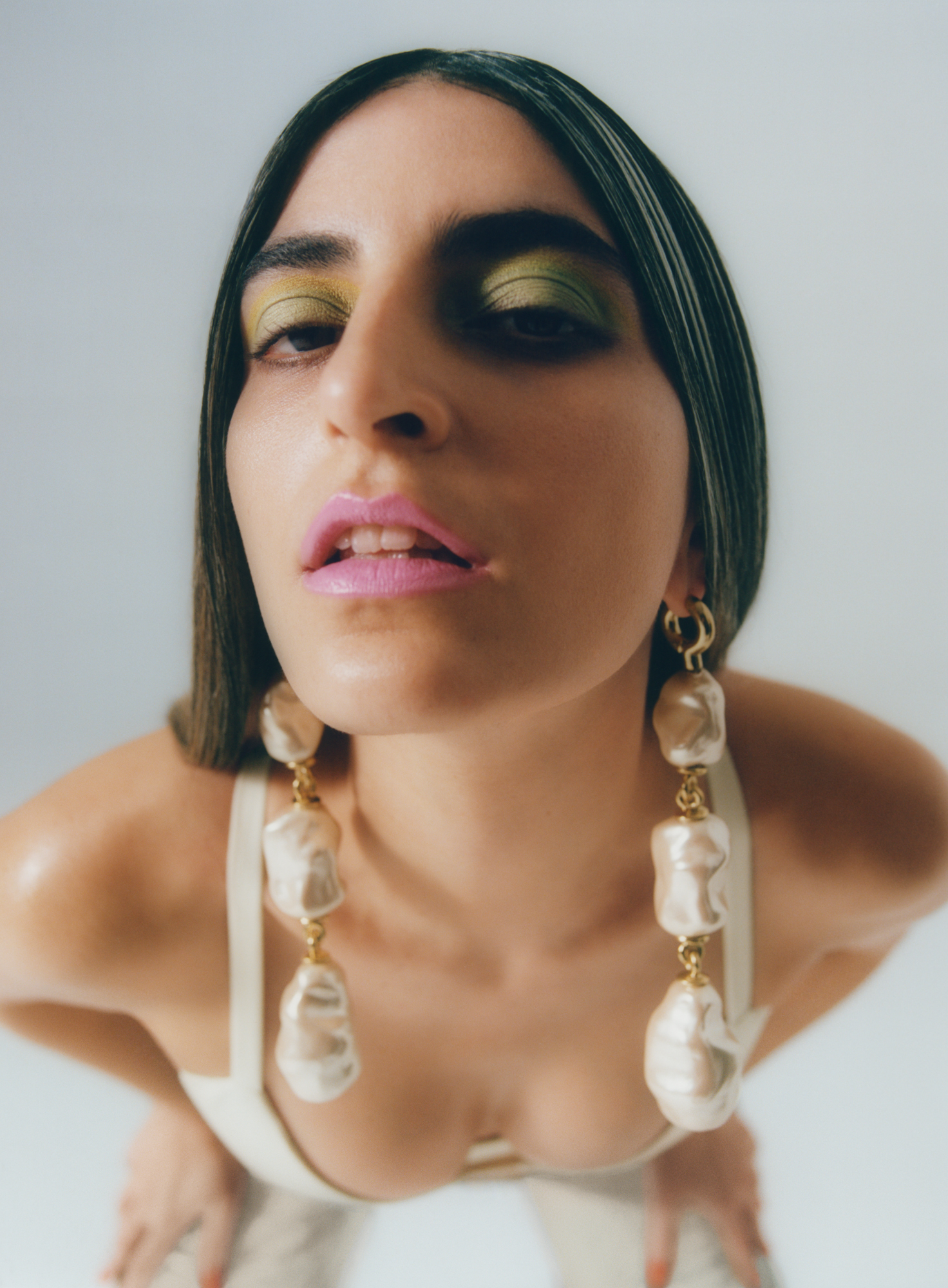 Model leaning towards camera with pearl earrings