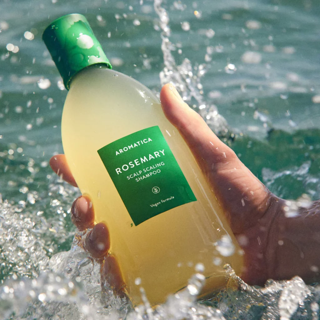 Aromatica shampoo bottle in hand in ocean.