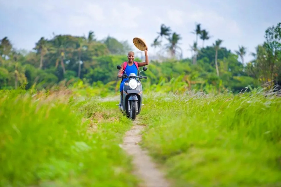 woman riding motorbike through grass field in Bali