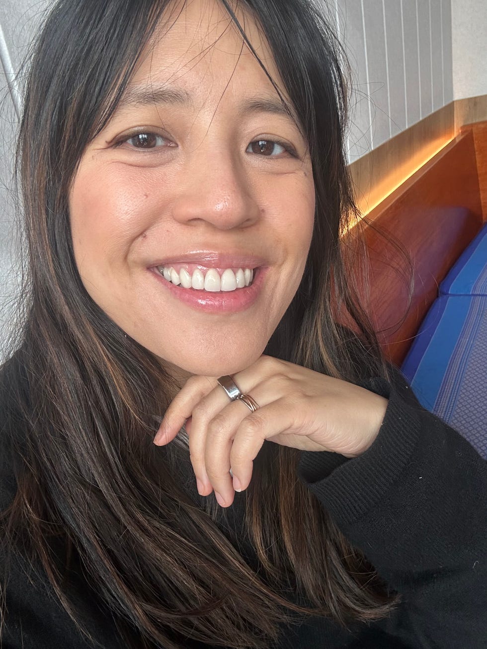 A person with long hair wearing a black sweater and displaying their hand.