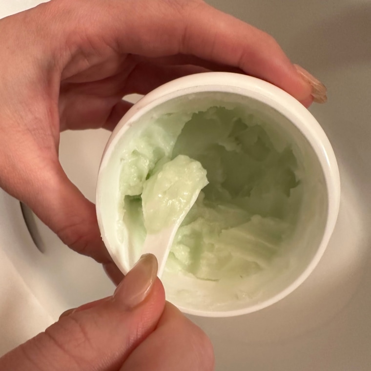 Woman scooping out cleansing balm from tub
