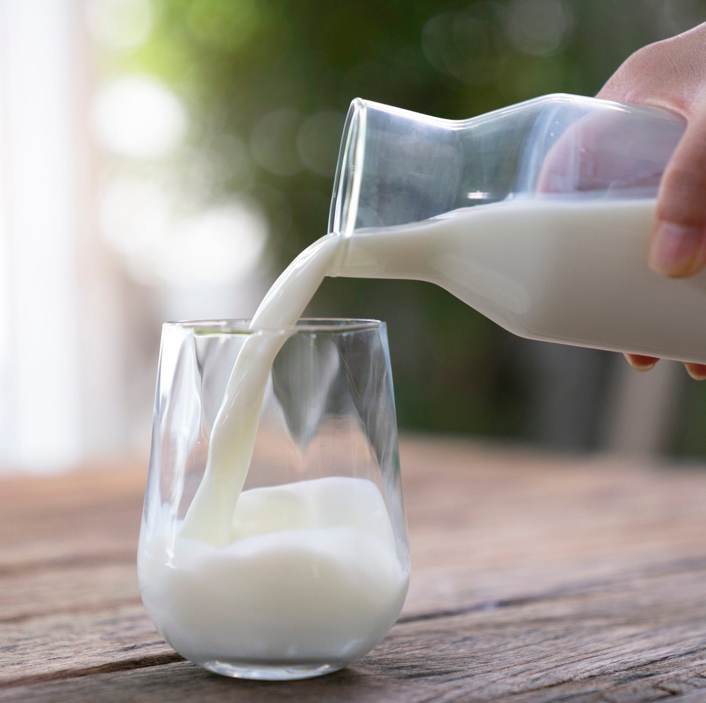 the milk is poured into a ceramic jug into a glass on a natural background