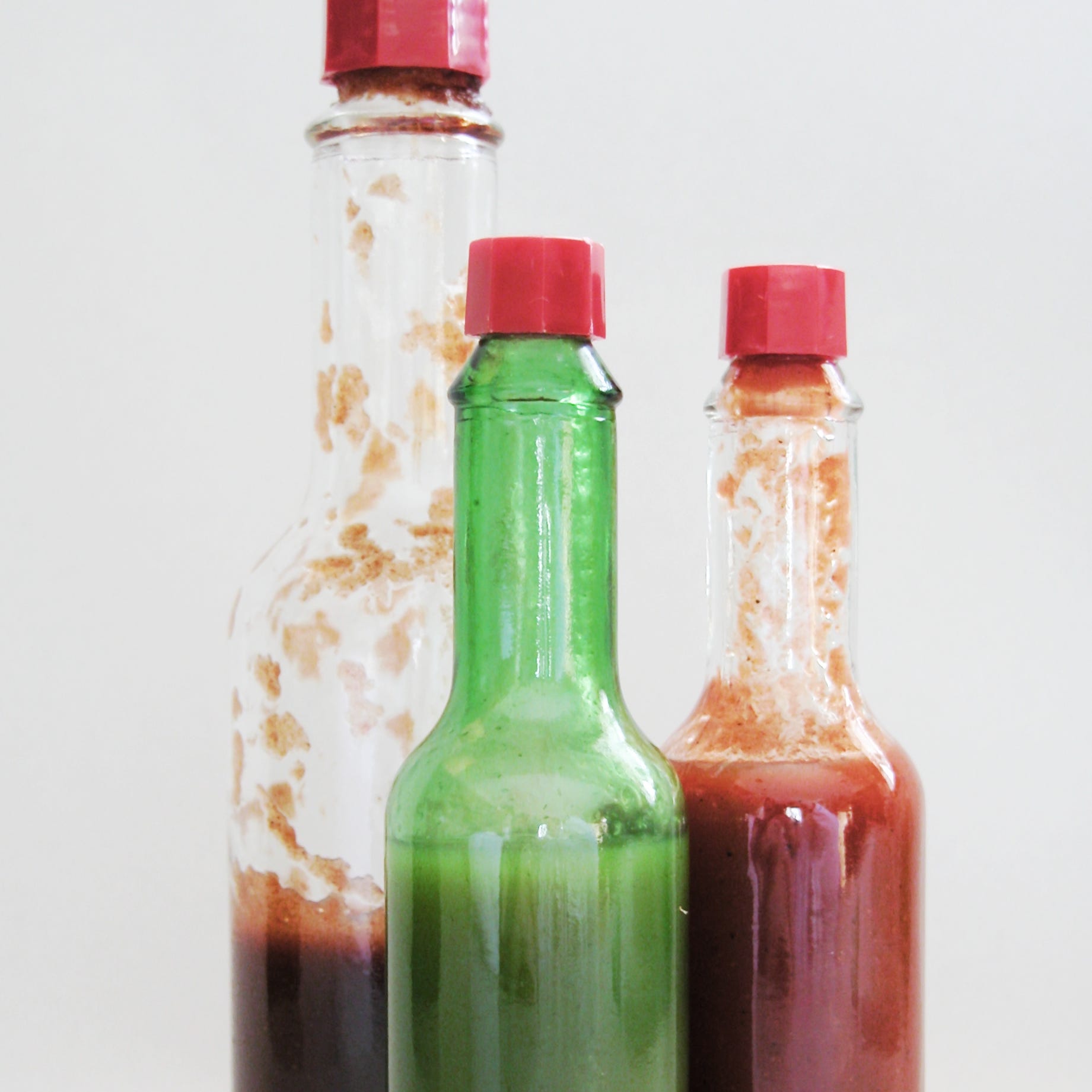 three bottles of hot sauce, jalapeno, tobasco, and chipolte