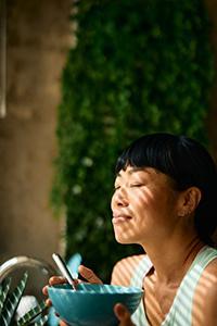 A young woman enjoys a healthy breakfast in a sunlit kitchen, relishing a moment of peace and mindfulness while embracing a balanced, nourishing morning routine.