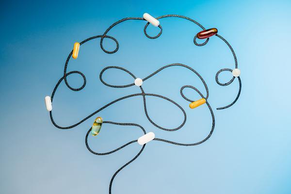 Illustration of a human brain formed by a black wire with assorted colorful medicine capsules attached.