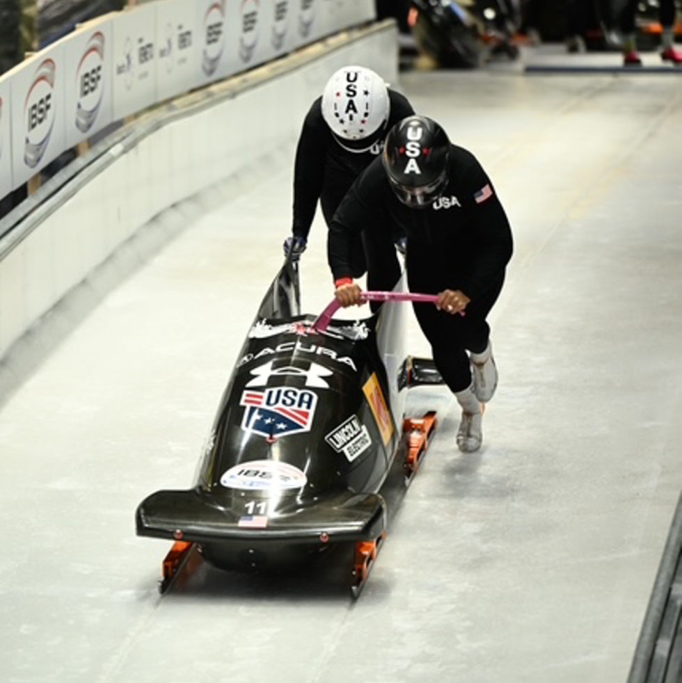 two athletes pushing a bobsled at a training facility