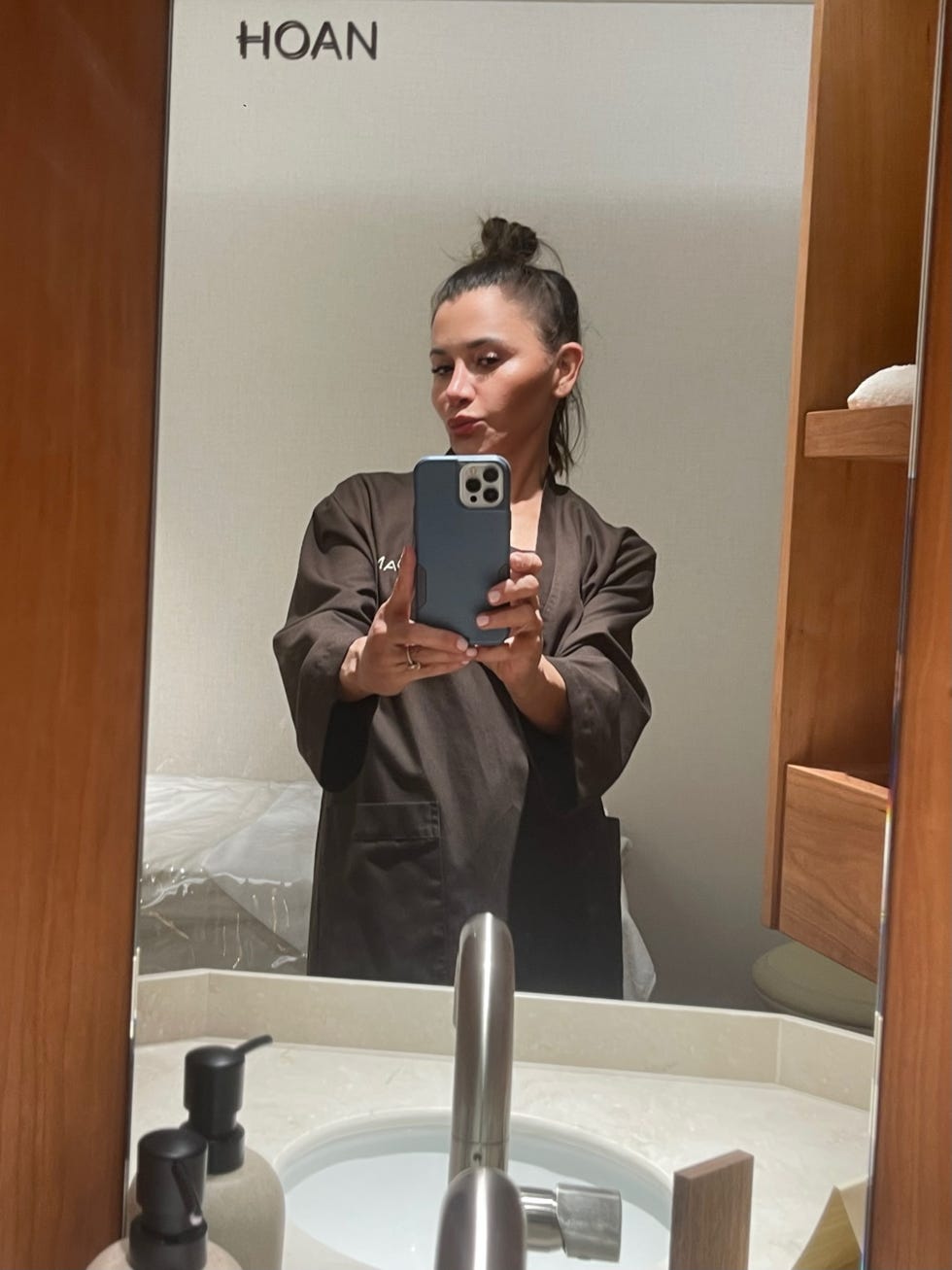 a person in a brown robe taking a selfie in a bathroom mirror a person in a brown robe taking a selfie in a bathroom mirror