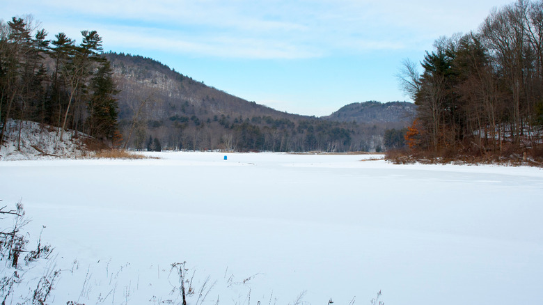 Lake covered in snow surrounded by trees in winter at Moreau Lake State Park near Corinth, New York