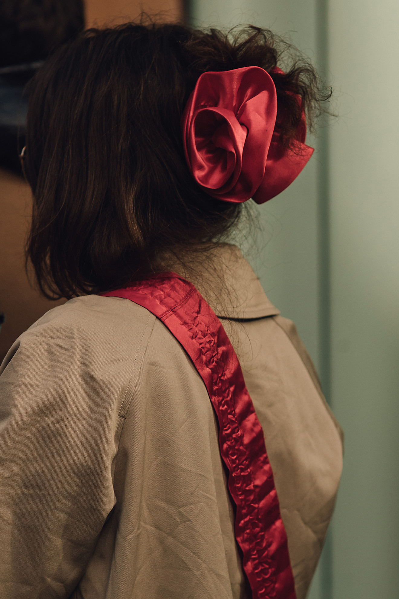 A side profile of a woman wearing a red satin scrunchie tied into a her bun hairstyle