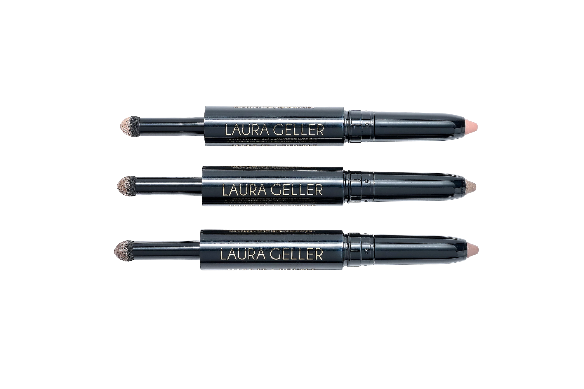 Three Laura Geller eye shadow sticks, each with a sponge applicator on one end and an eye shadow crayon on the other.