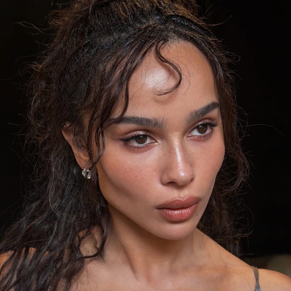 portrait of a person with curly hair wearing a grey top