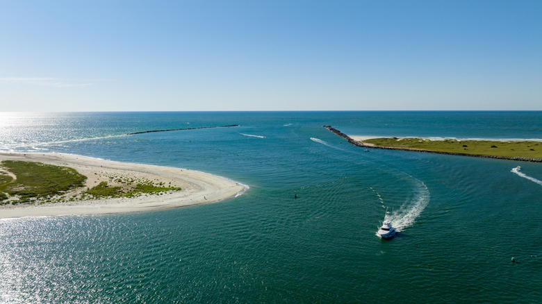 Aerial view of boats cruising through the Masonboro Inlet next to white-sand beaches on a sunny day.