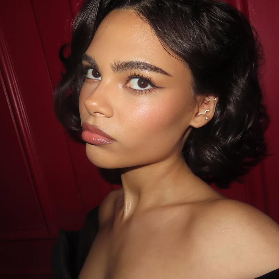 person with shoulderlength wavy hair against a red background