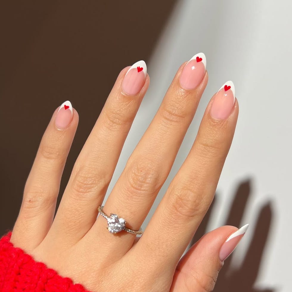 a hand displaying manicure with heart designs and a ring a hand displaying manicure with heart designs and a ring