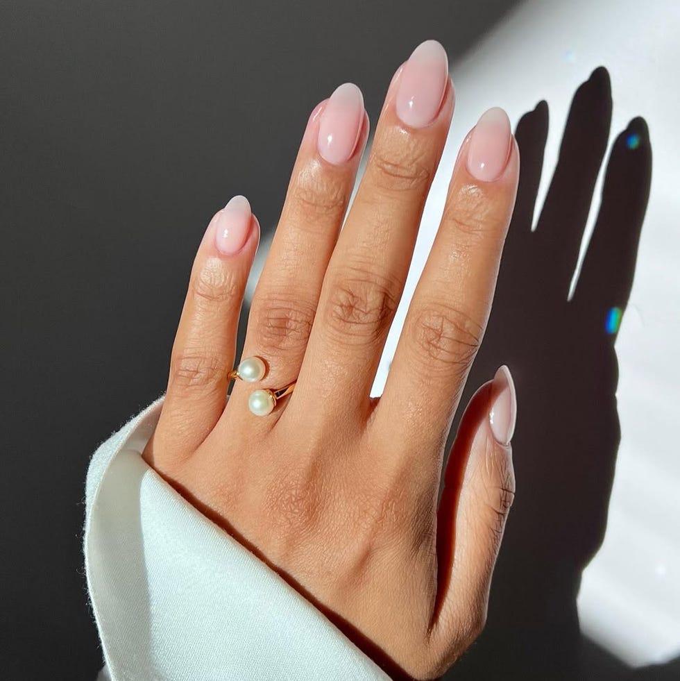 manicured hand displaying elegant pink nails and a pearl ring manicured hand displaying elegant pink nails and a pearl ring