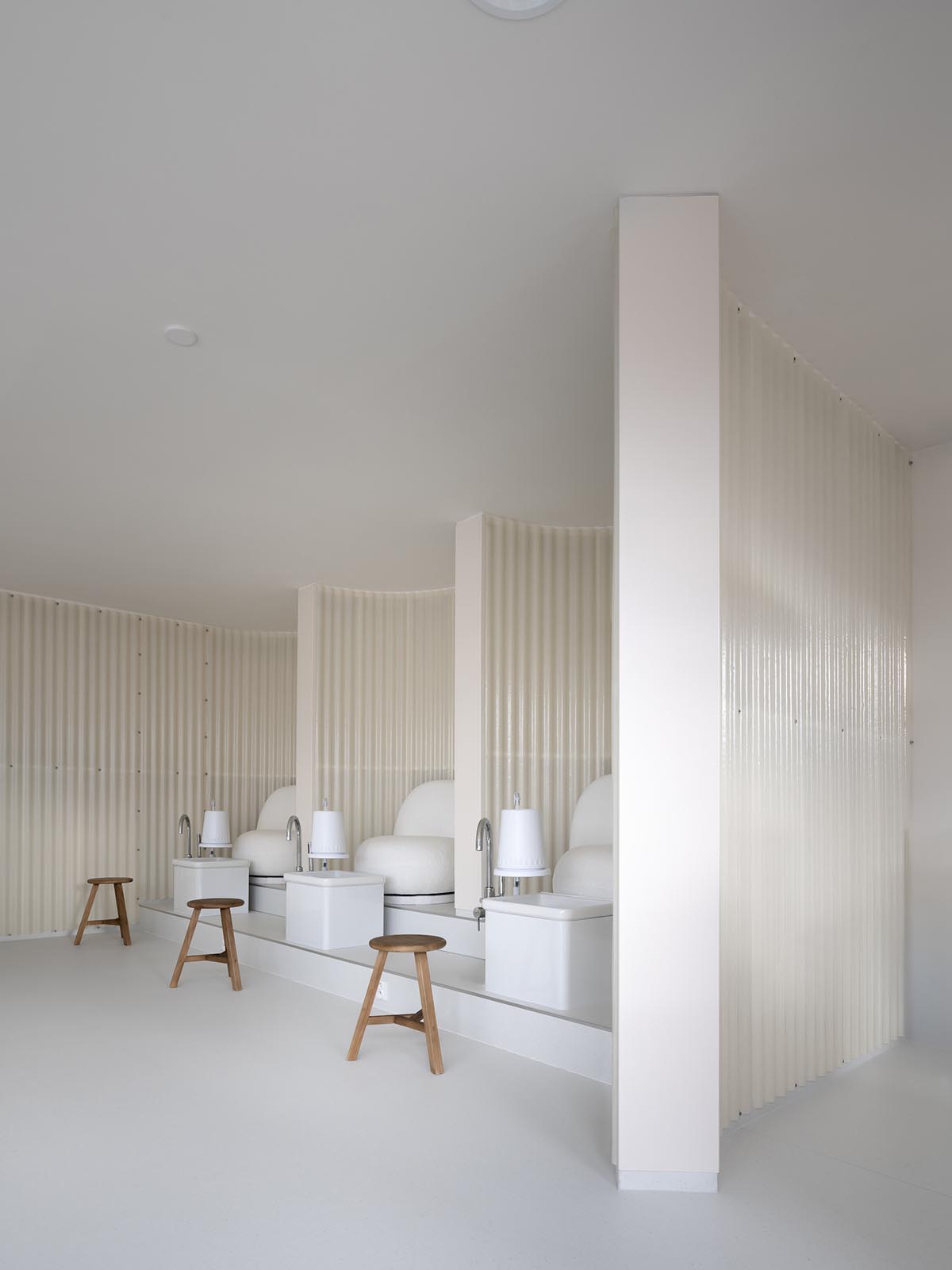 A beauty salon brings warm light with translucent partitions and tactile elements in Prague