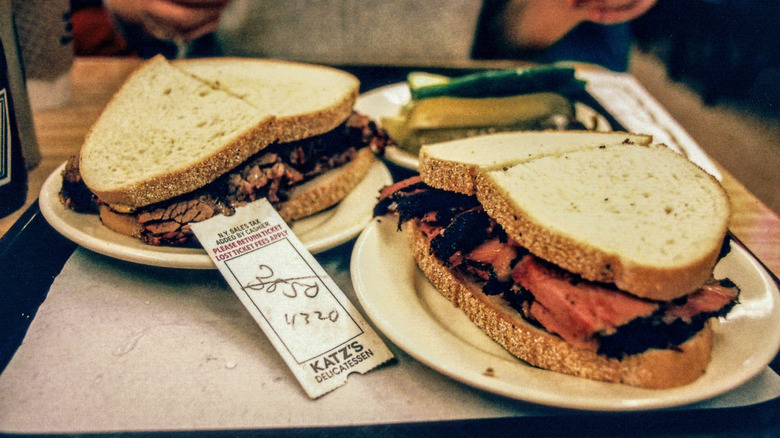 a brisket and a pastrami sandwich on table with bill