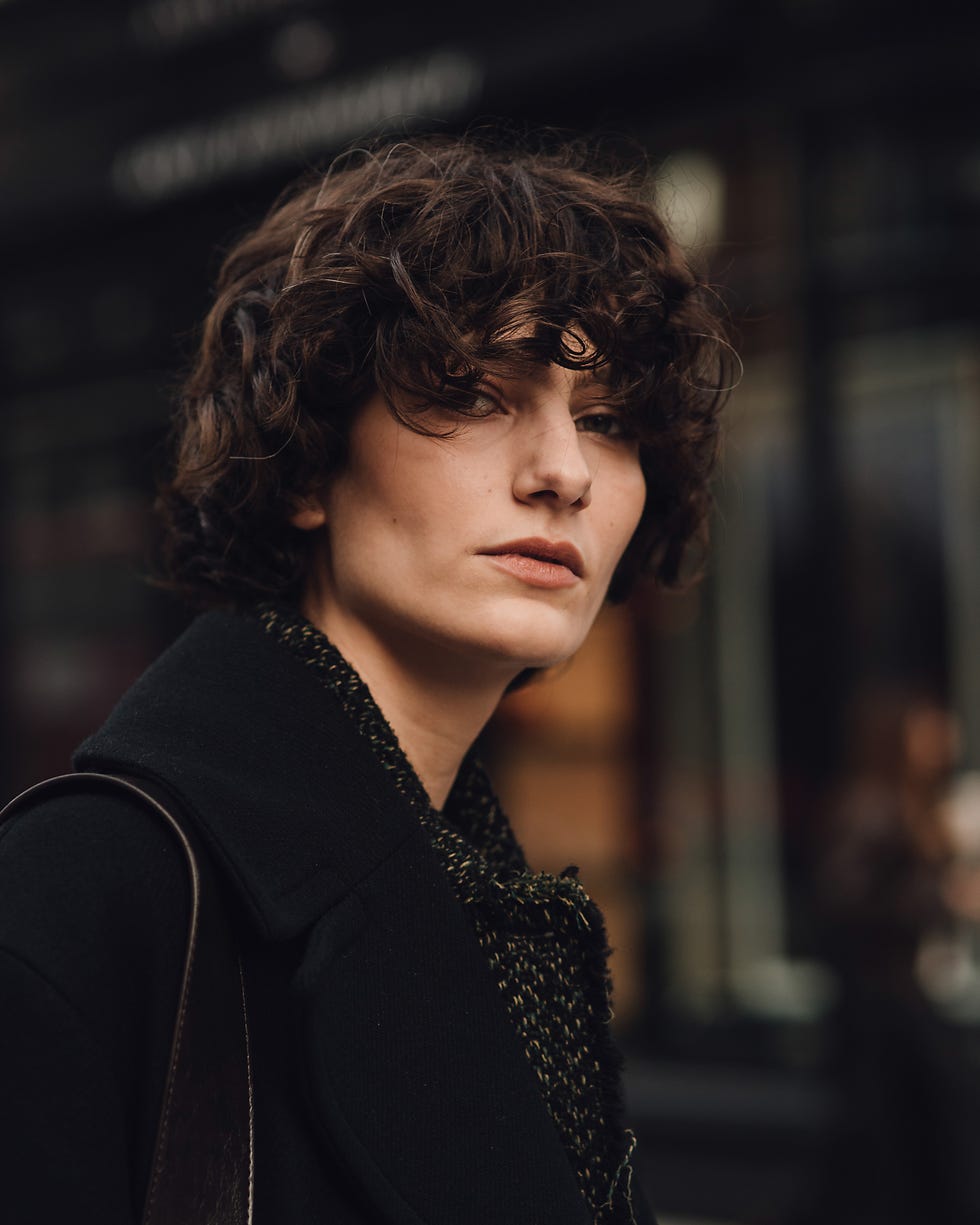 person wearing a dark coat and scarf in an urban setting