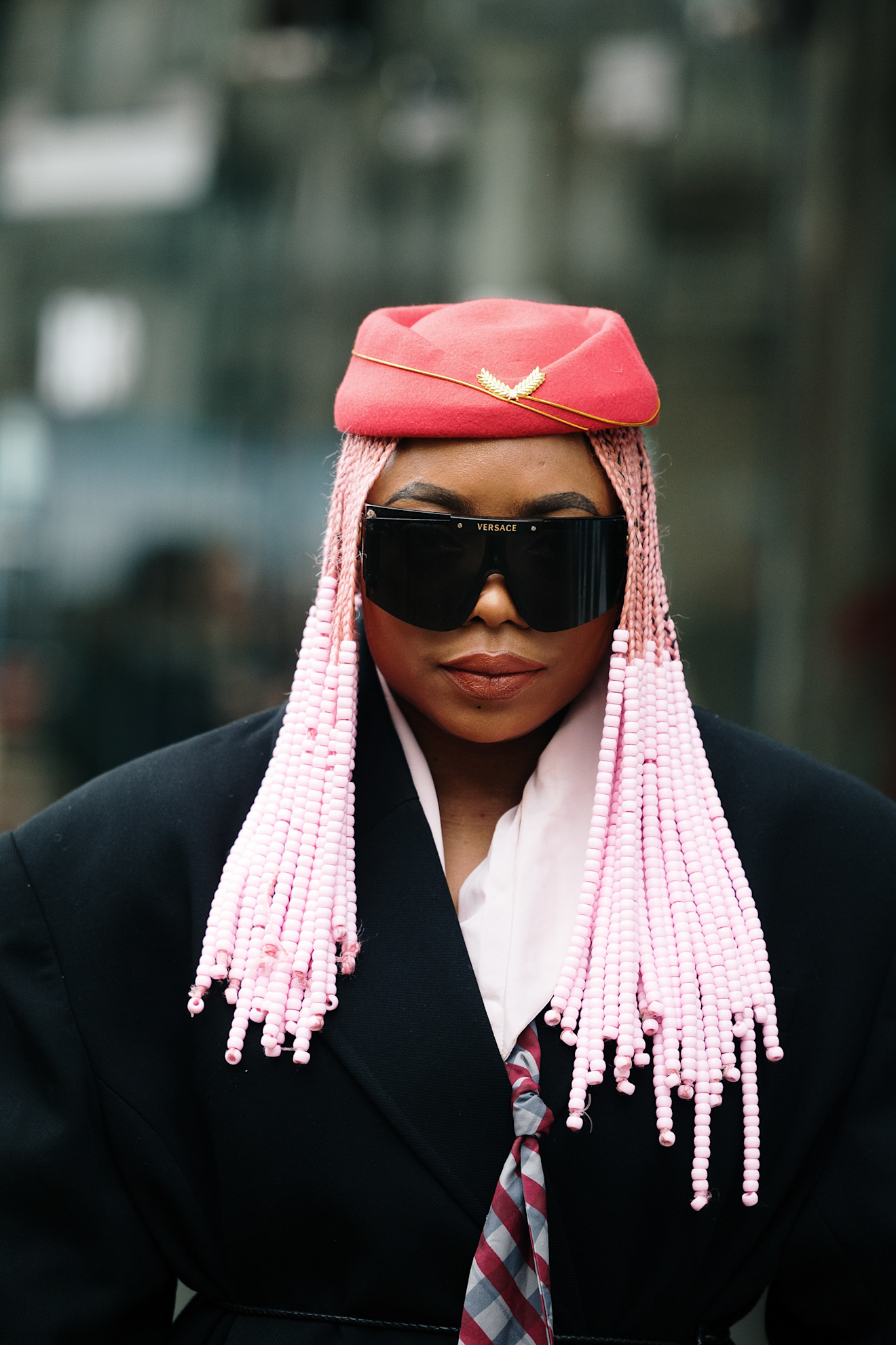 A woman with bright pink braids, which have pink beads through the mid-lengths