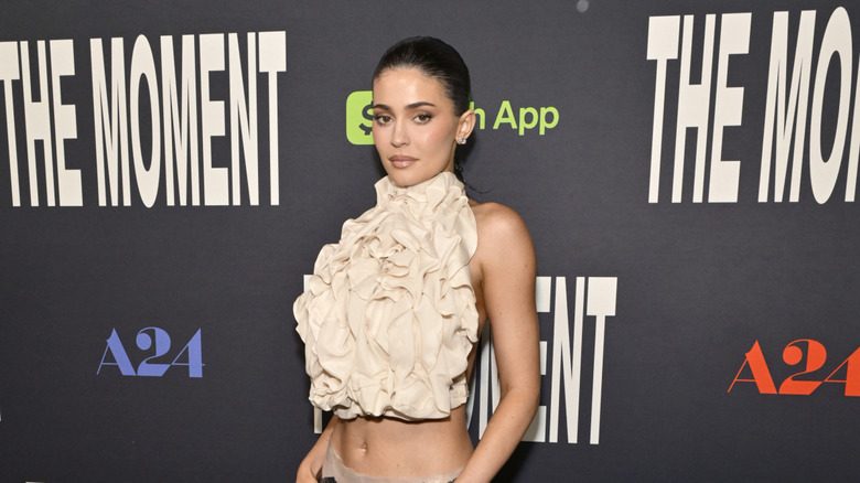 Kylie Jenner in cream colored ruffled top with bare midriff