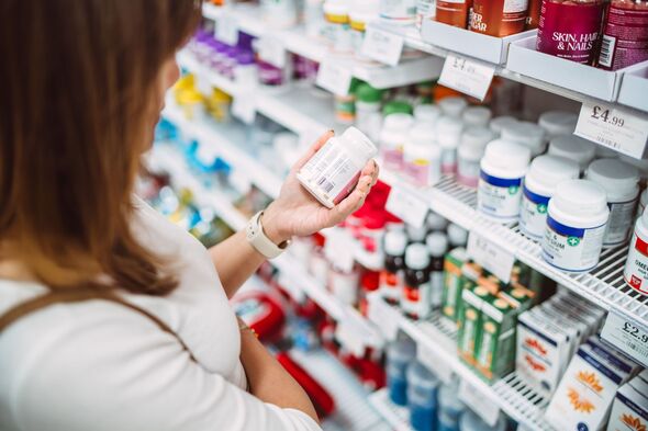 Woman choosing vitamins in pharmacy aisle Woman choosing vitamins in pharmacy aisle