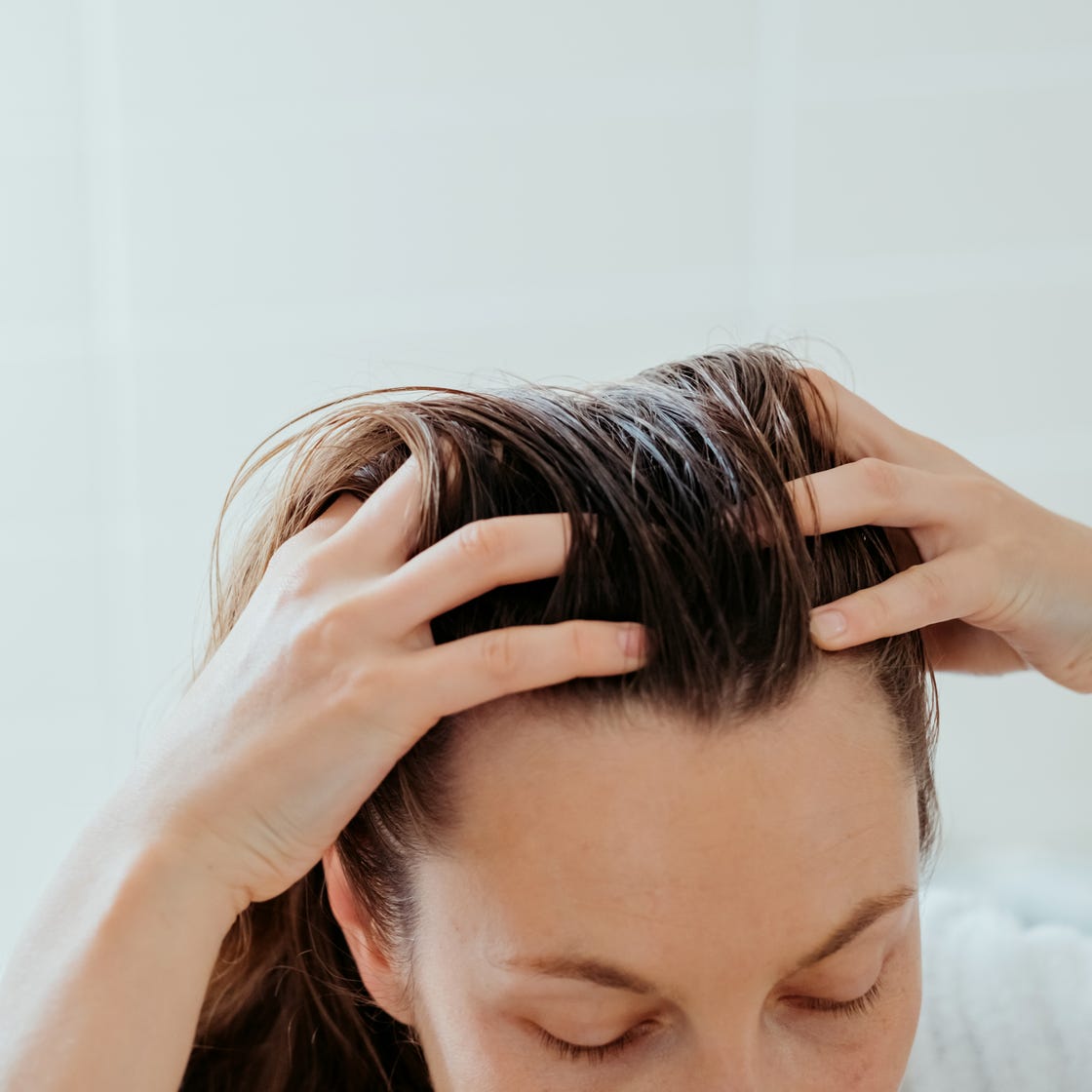 woman delicately doing massage of her scalp with cosmetic oil.