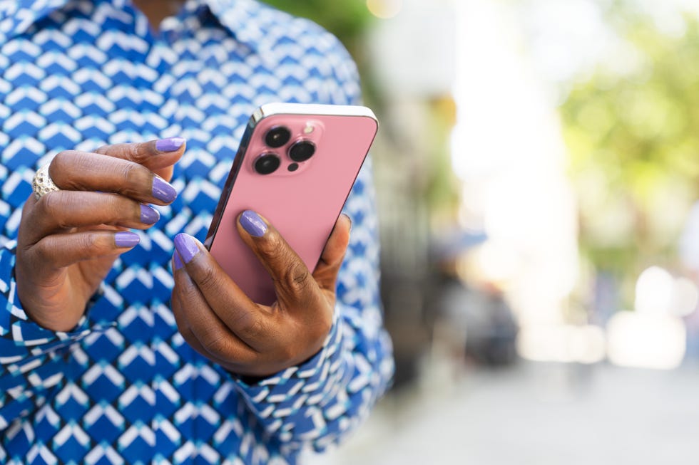 a person holding a pink smartphone outdoors