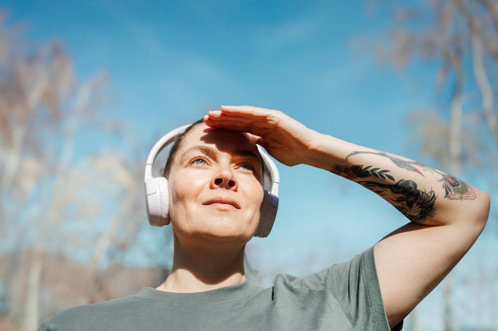 Woman looks into the distance and  shielding eyes from sun with her hand