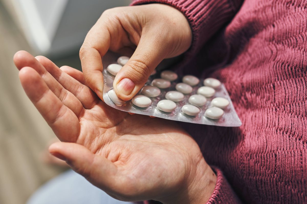 Close perspective of hands carefully holding a blister pack with white pills, emphasizing health and medication concepts.