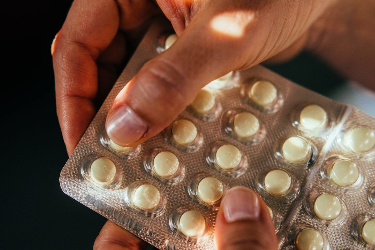 Hand taking medicin pill out of a blister.