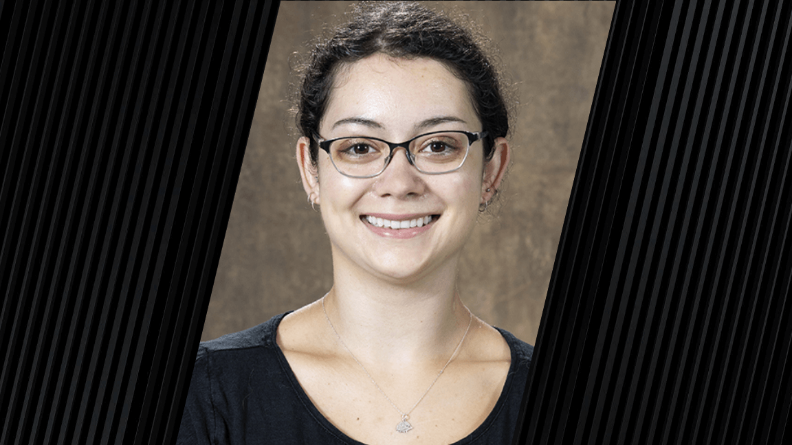 Portrait of a woman with dark hair, wearing glasses and a black shirt