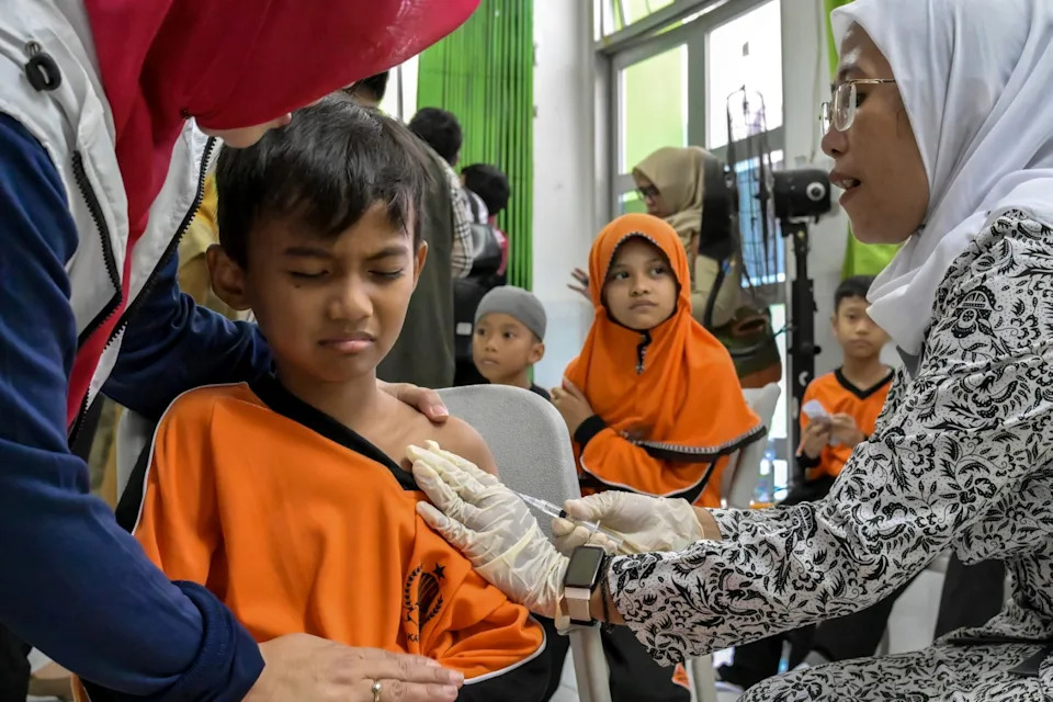 <span>A healthcare worker administers the measles vaccine to an elementary school student during the launch of a free health check programme for children, in Jakarta on August 4, 2025.</span><div><span>BAY ISMOYO</span><span>AFP</span></div>