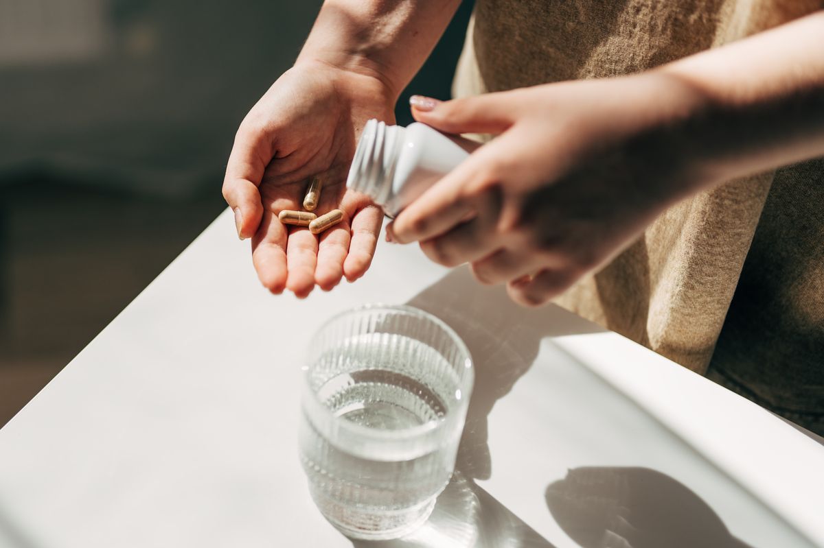 Hand with pills and water glass