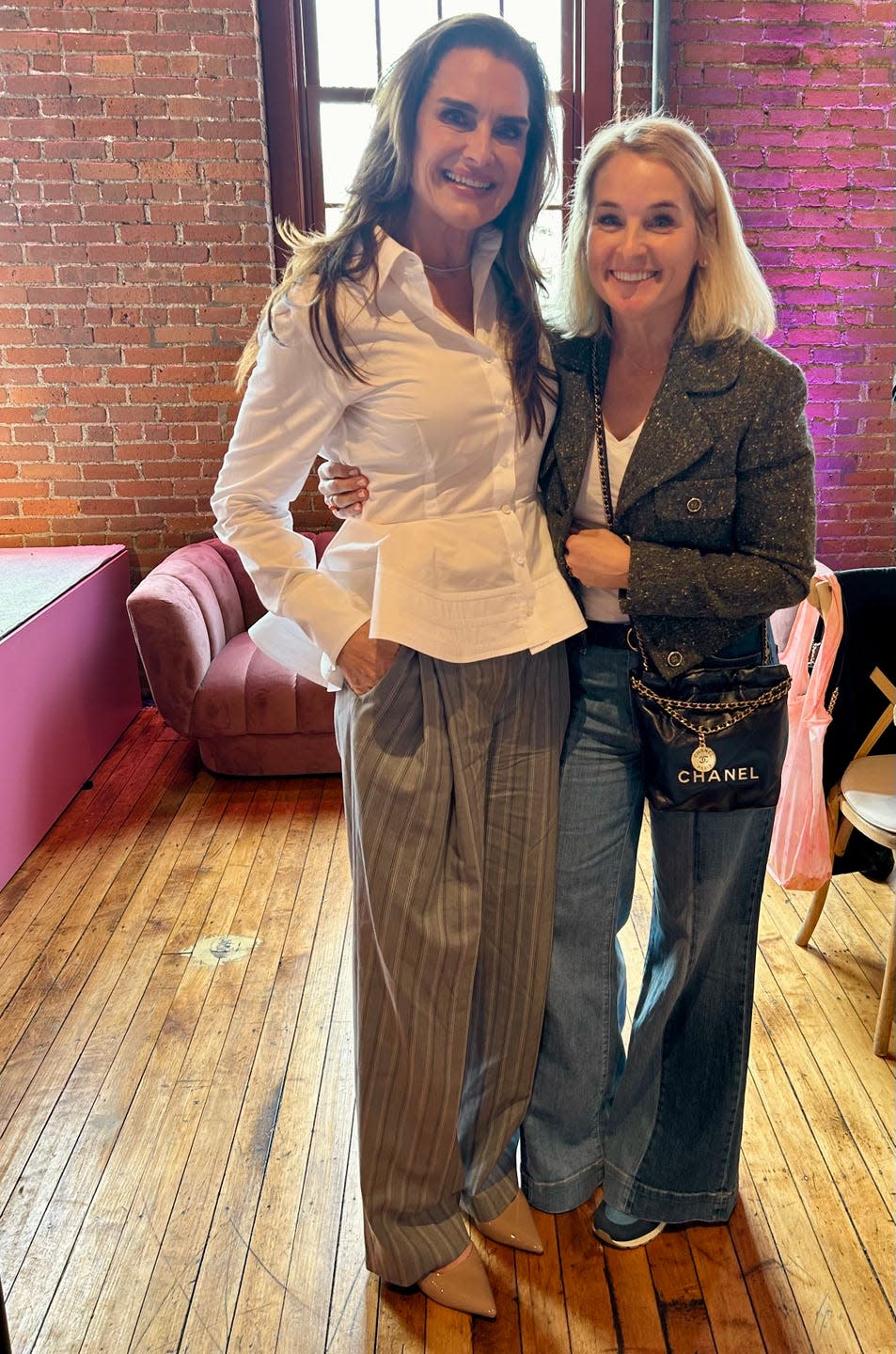 two women posing together in a casual setting with fashionable outfits