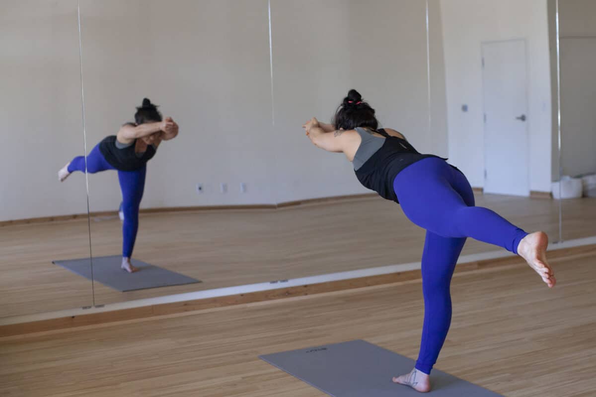Alameda Post - A woman holds a yoga pose at a fitness studio.