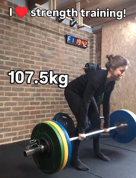 A woman performing a deadlift with a barbell loaded with 107.5kg.