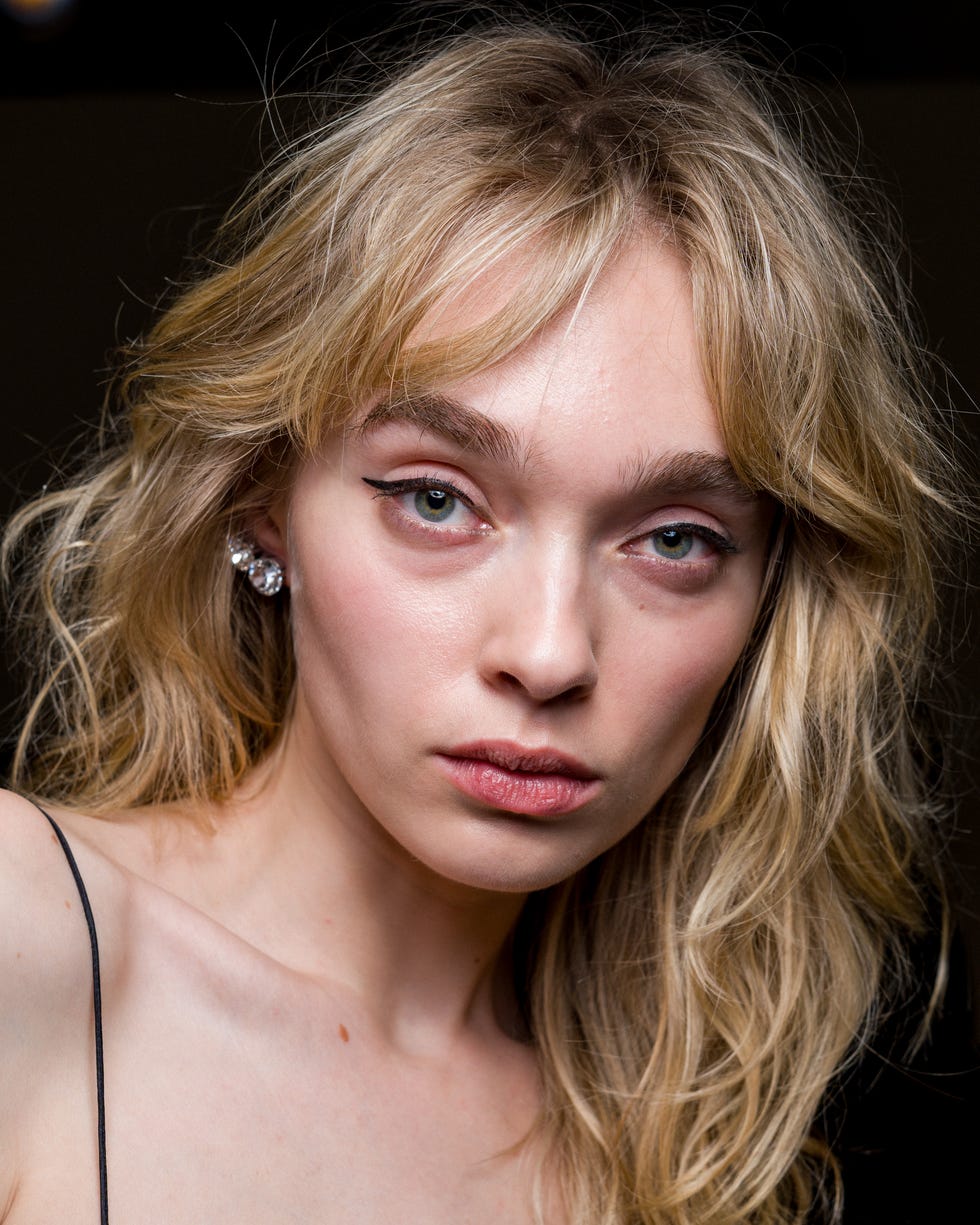 blurry image of a person with long wavy hair and earrings focusing on the upper body blurry image of a person with long wavy hair and earrings focusing on the upper body
