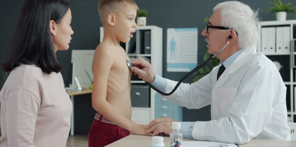 Doctor examines a young boy's chest with stethoscope.
