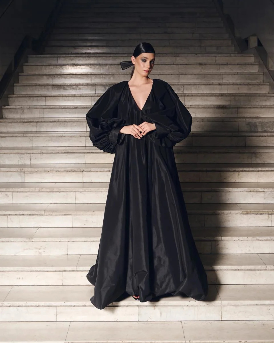 A model wears a full length black dress with a deep V-neckline.