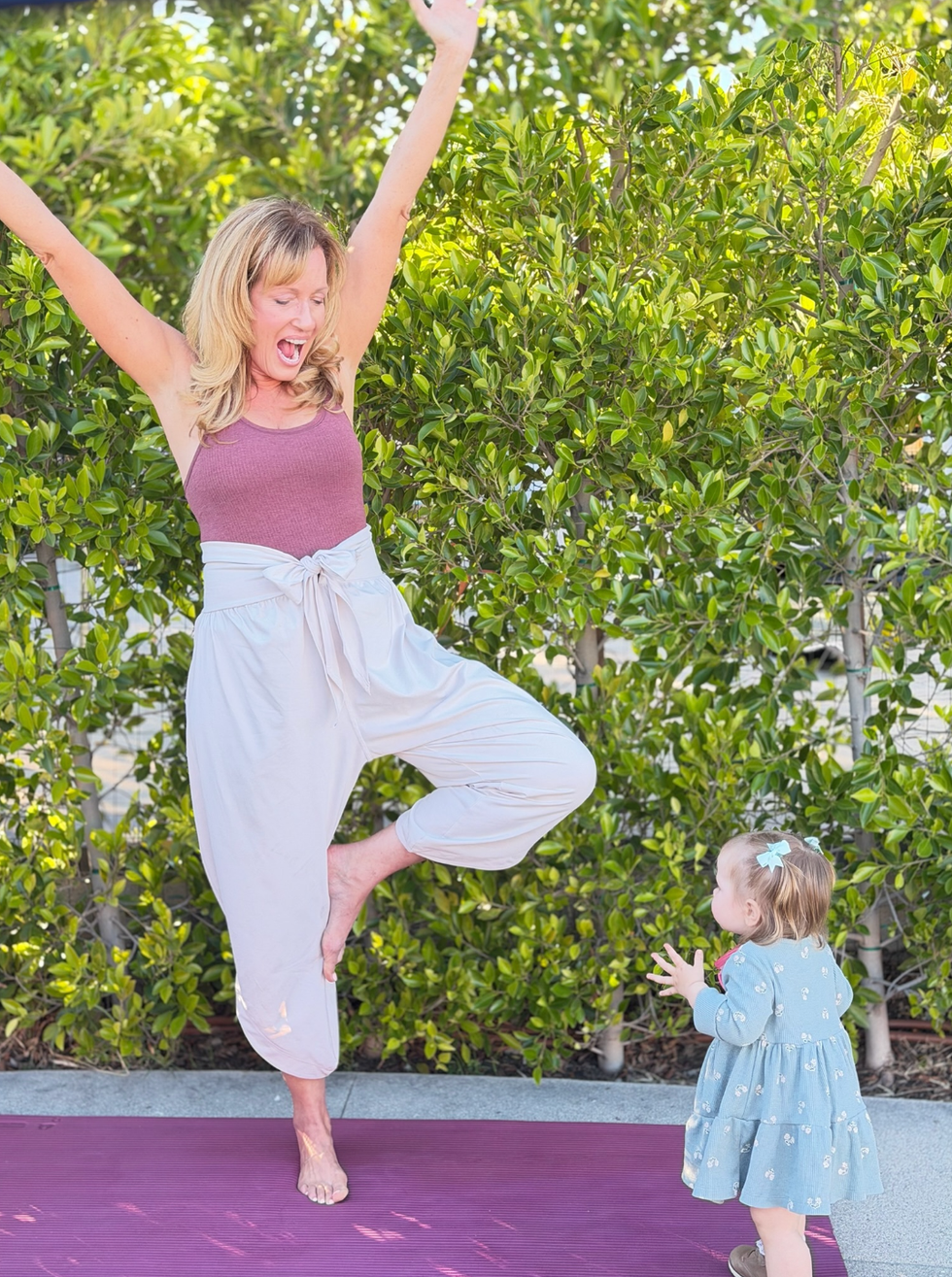 adult performing a yoga pose in front of a child