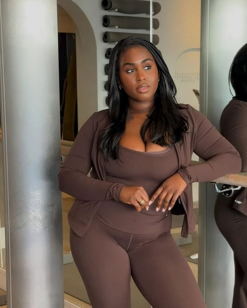 individual posing in a fitness studio wearing brown activewear