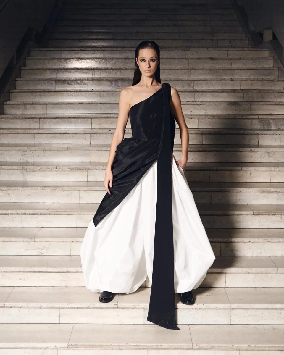 A model wears voluminous white pants and an asymmetric black top.