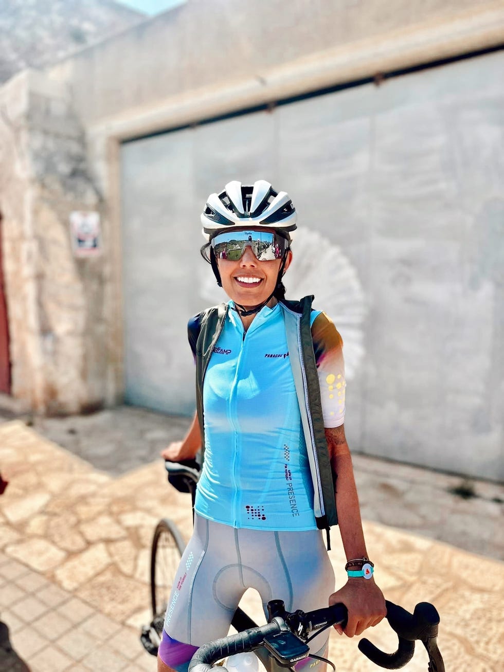 Cyclist in a blue cycling outfit with a helmet, standing beside a bike.