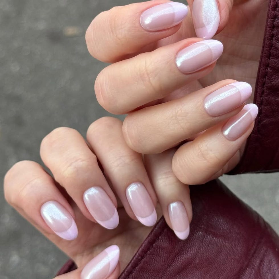 Manicured hands with a stylish nail design featuring a nude base and pink tips.