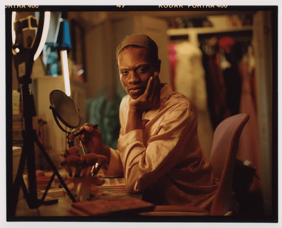 Shamari sits at a vanity applying makeup in a warmly lit room in South Carolina.